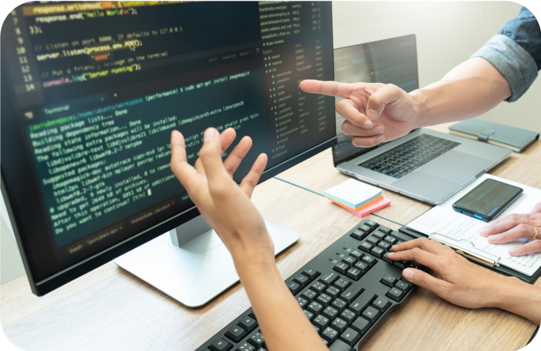 大画面モニターでプログラムを確認しながら打ち合わせするエンジニア